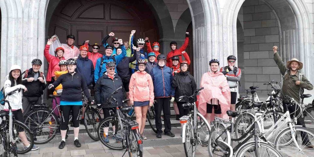 Grupa uczestników wycieczki rowerowej przed zabytkowym budynkiem